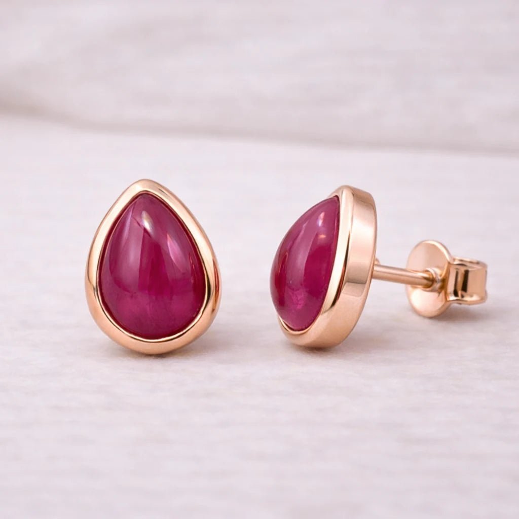 Rose gold stud earrings with july birthstone tear drop shaped natural ruby gemstones on a light background