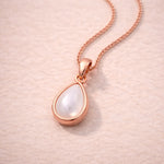 Rose Gold necklace with a teardrop-shaped natural mother of pearl pendant on a soft pink background