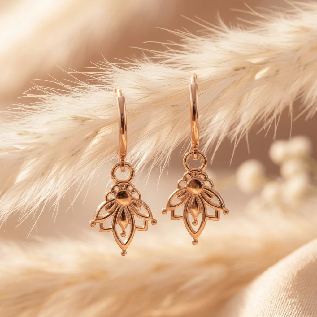 Rose gold lotus hoop earrings with lotus charms on soft beige