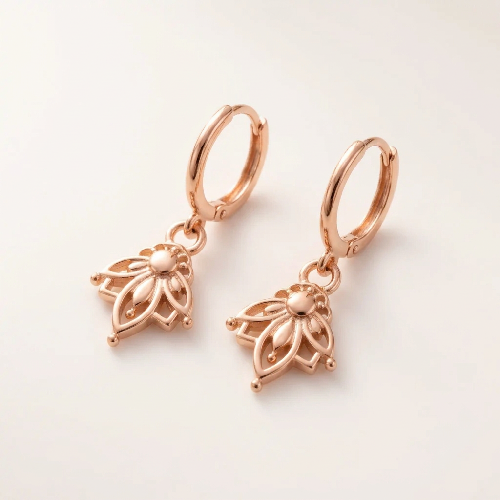 Pair of rose gold lotus hoop earrings with openwork lotus charms on a plain cream background