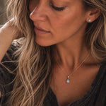 model wearing rose gold march birthstone jewellery set of dainty natural aquamarine pendant necklace and matching stud aquamarine earrings