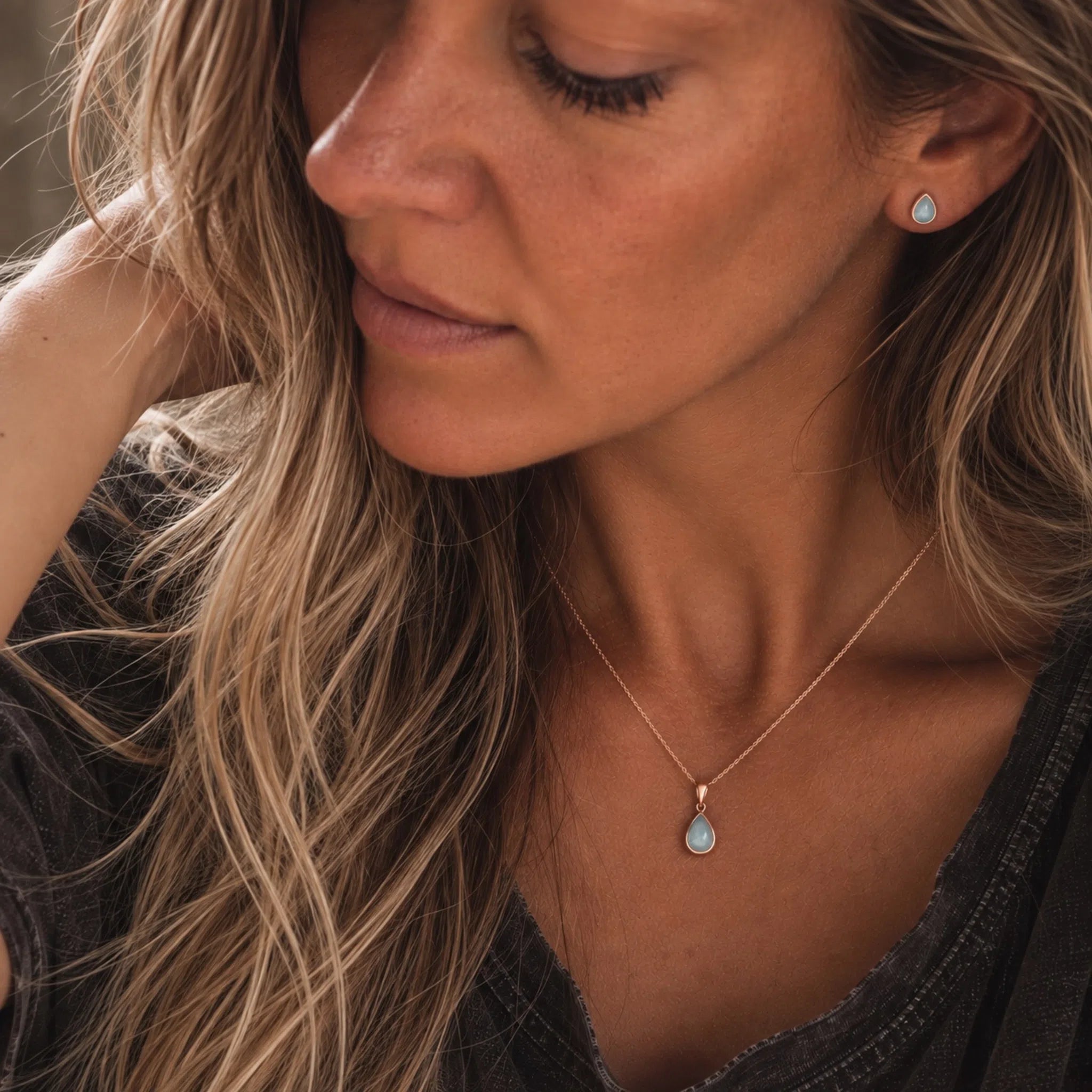 model wearing rose gold march birthstone jewellery set of dainty natural aquamarine pendant necklace and matching stud aquamarine earrings