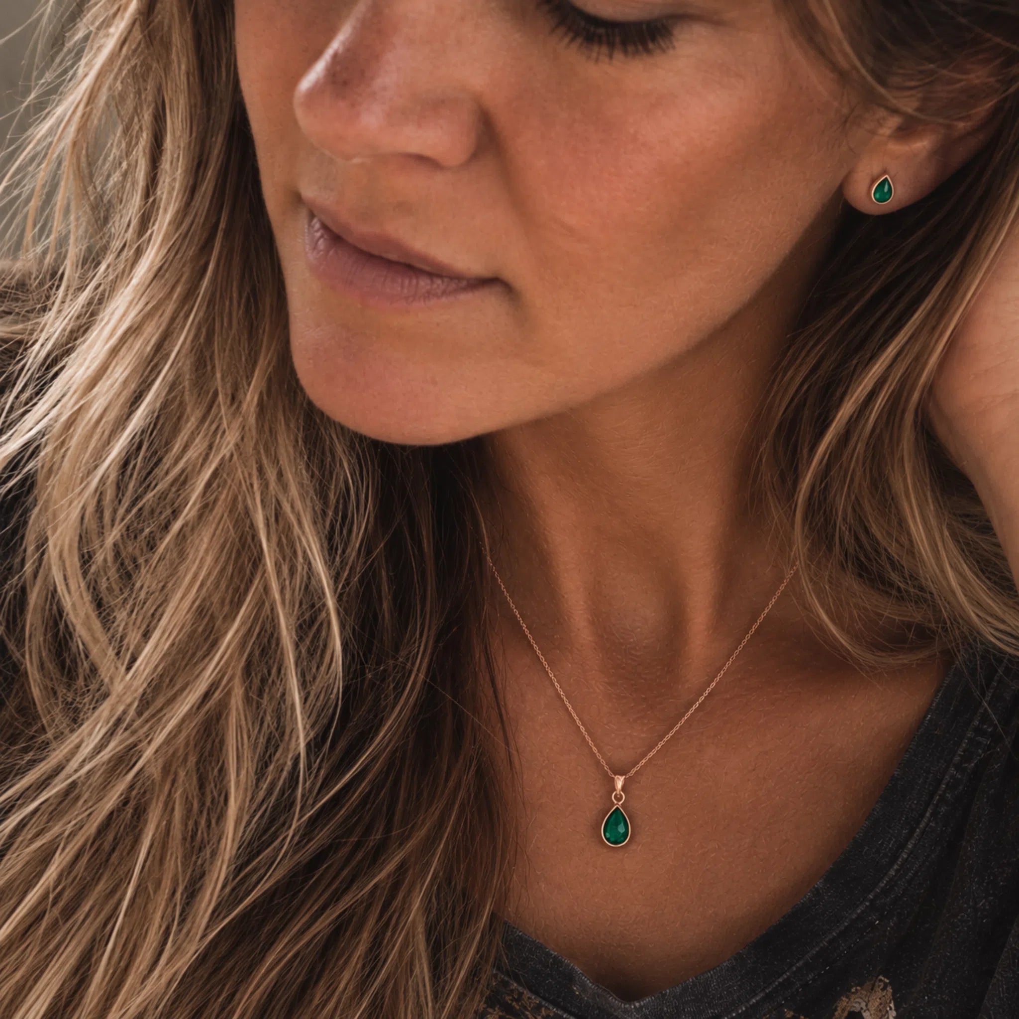 model wearing rose gold may birthstone jewellery set of dainty natural emerald pendant necklace and matching stud emerald earrings