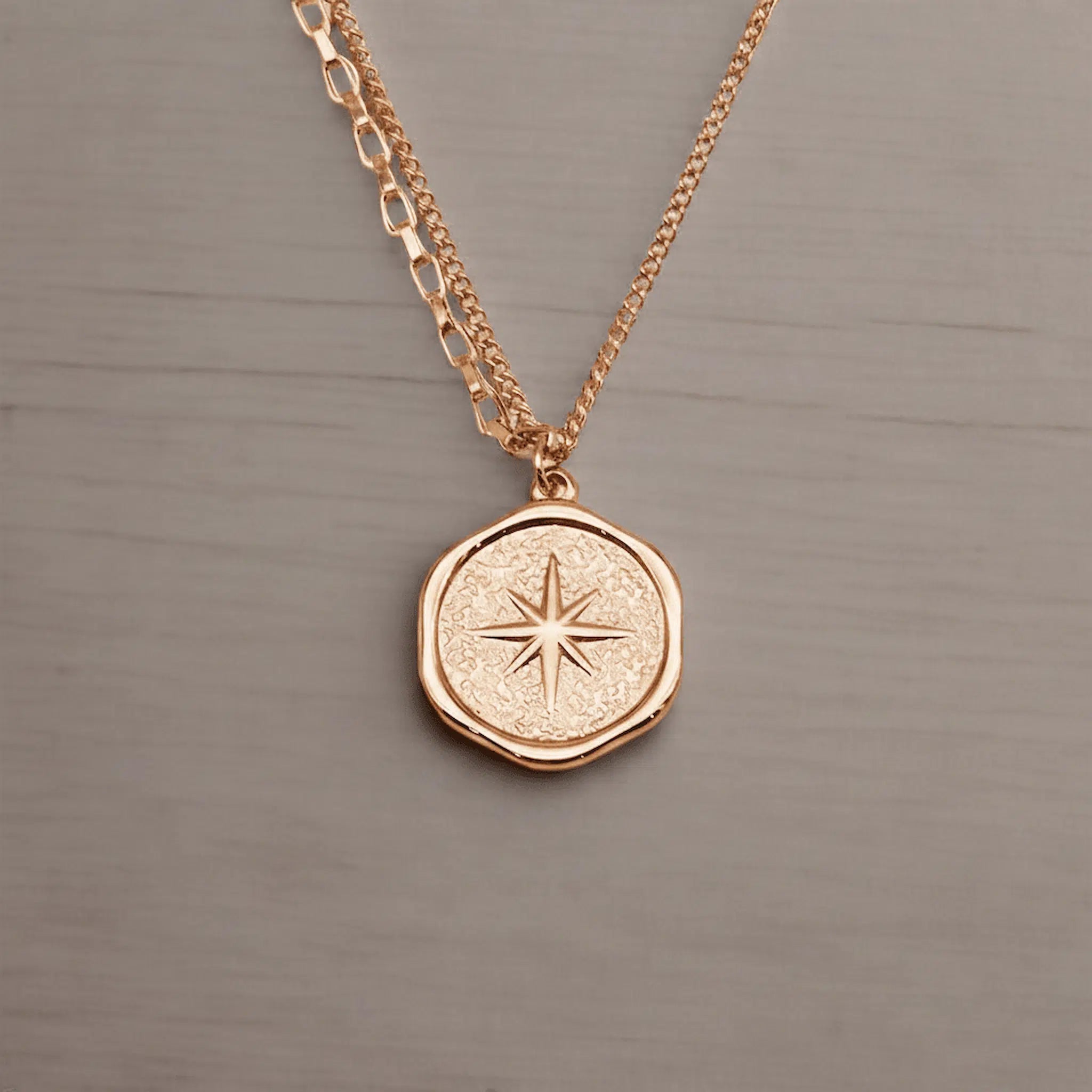 Rose gold necklace with a star pendant on a gray background