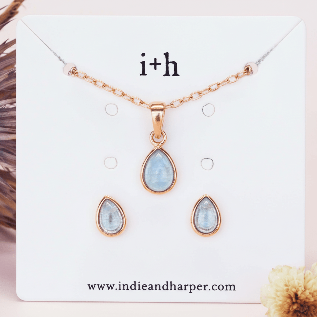 Jewelry set with rose gold teardrop pendants on a display card with 'i+h' branding.