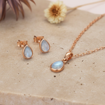 Blue topaz Jewelry set with rose gold necklace and earrings light stone surface