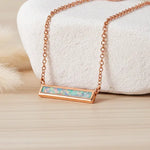 Rose gold necklace with an opal pendant on a soft white background