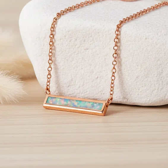 Rose gold necklace with an opal pendant on a soft white background