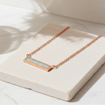 Rose gold necklace with a opal stone on a white surface