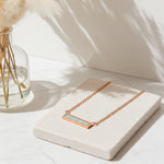 Rose gold necklace with a opal stone on a white surface