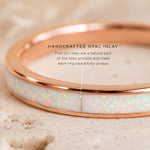 Rose gold ring with opal inlay on a beige background