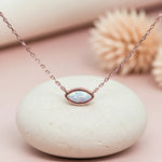 Necklace with an opal pendant on a white stone with a blurred natural background