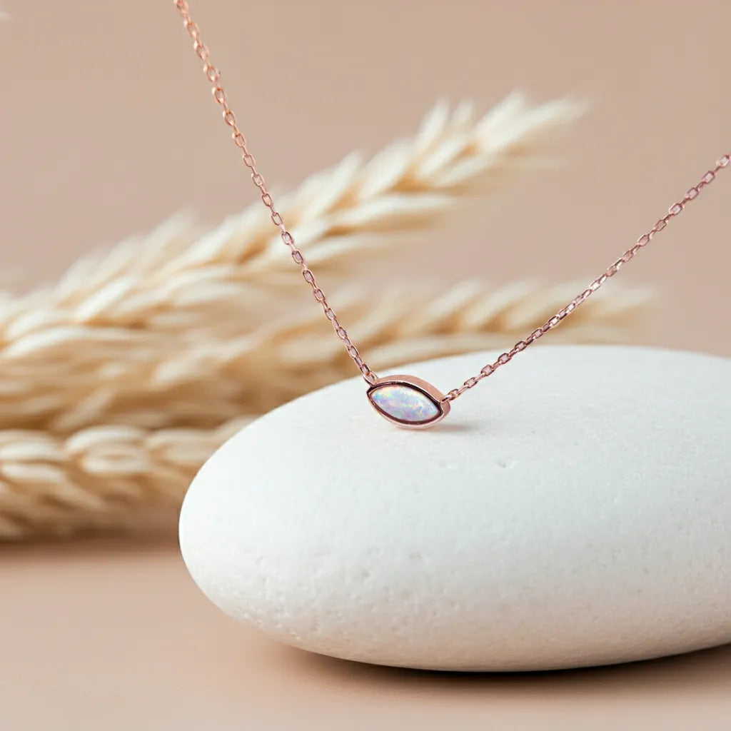 Rose gold necklace with a pendant on a white stone with wheat in the background