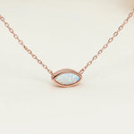 Necklace with an opal pendant on a white stone with a blurred natural background