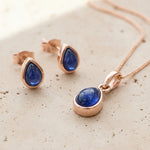 Jewellery set with september birthstone blue sapphire gemstones and rose gold accents on a textured surface