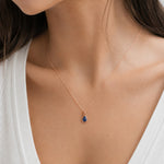 close up of model wearing a dainty rose gold september birthstone natural sapphire teardrop pendant necklace