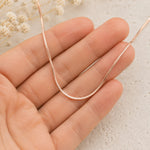 hand holding a dainty rose gold snake chain necklace