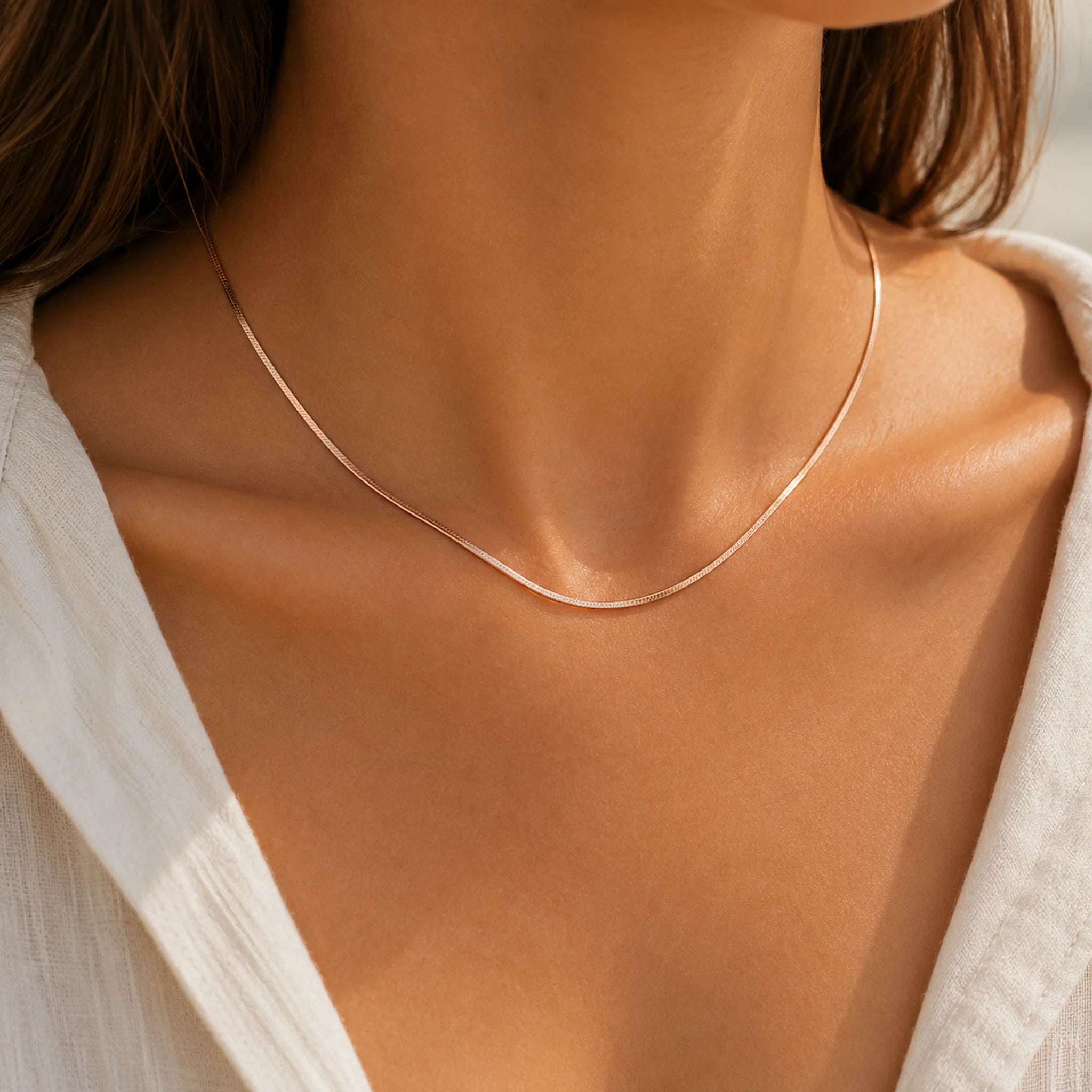 dainty rose gold snake chain necklace worn by a person wearing a white shirt