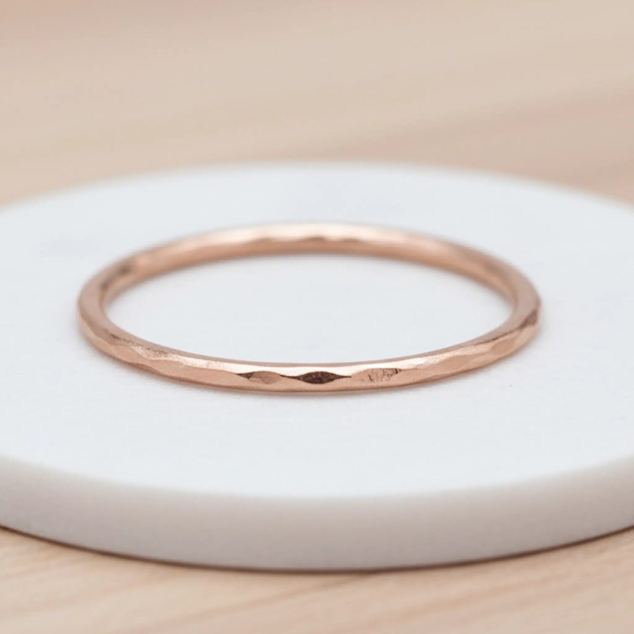 Rose gold hammered stacker ring on a white display surface, featuring a textured finish that reflects light softly.