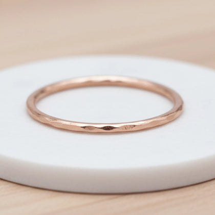 Rose gold hammered stacker ring on a white display surface, featuring a textured finish that reflects light softly.