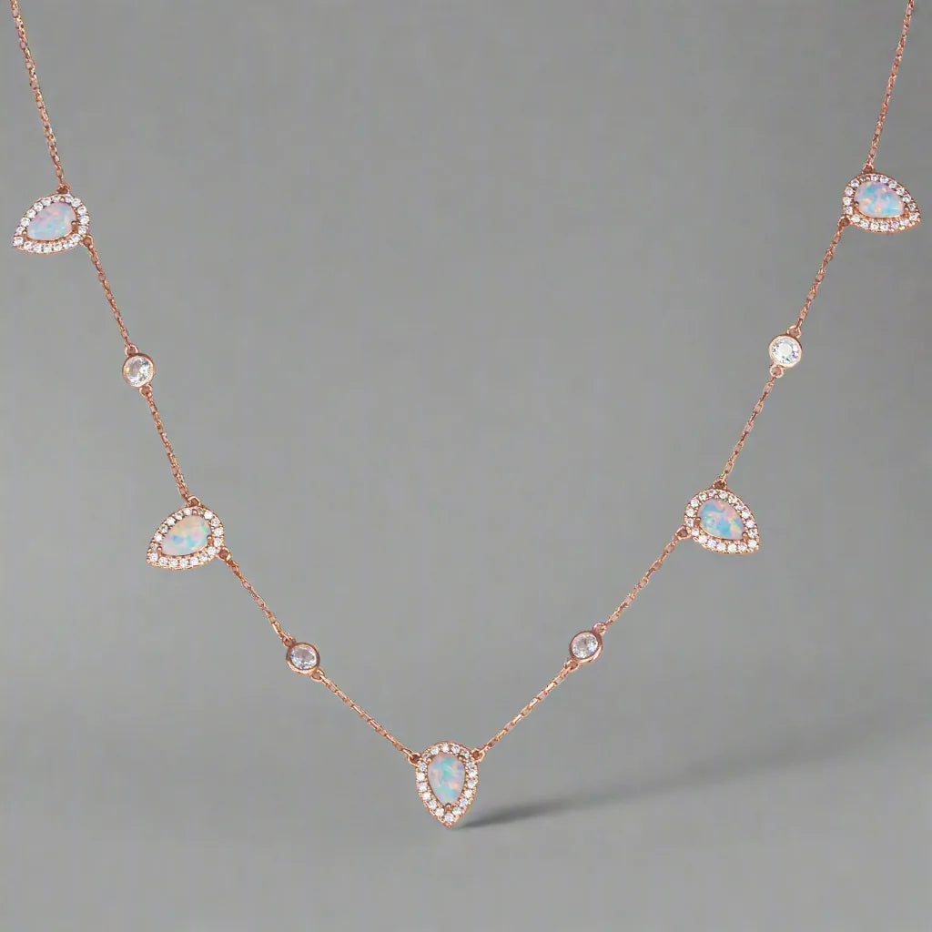 Rose gold necklace with opal stones on a gray background