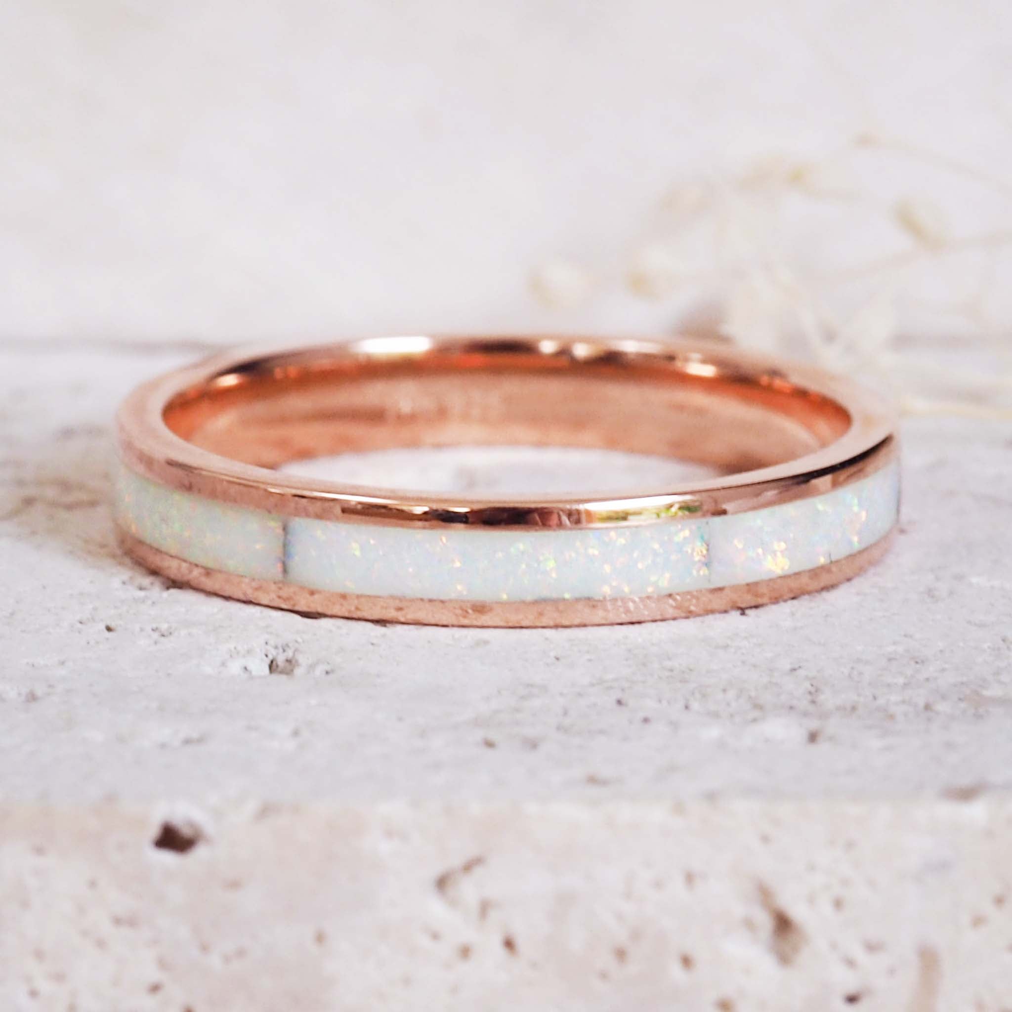 Rose gold ring with a white opal interior on a light marble background