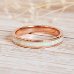 Rose gold ring with white opal interior on a light background