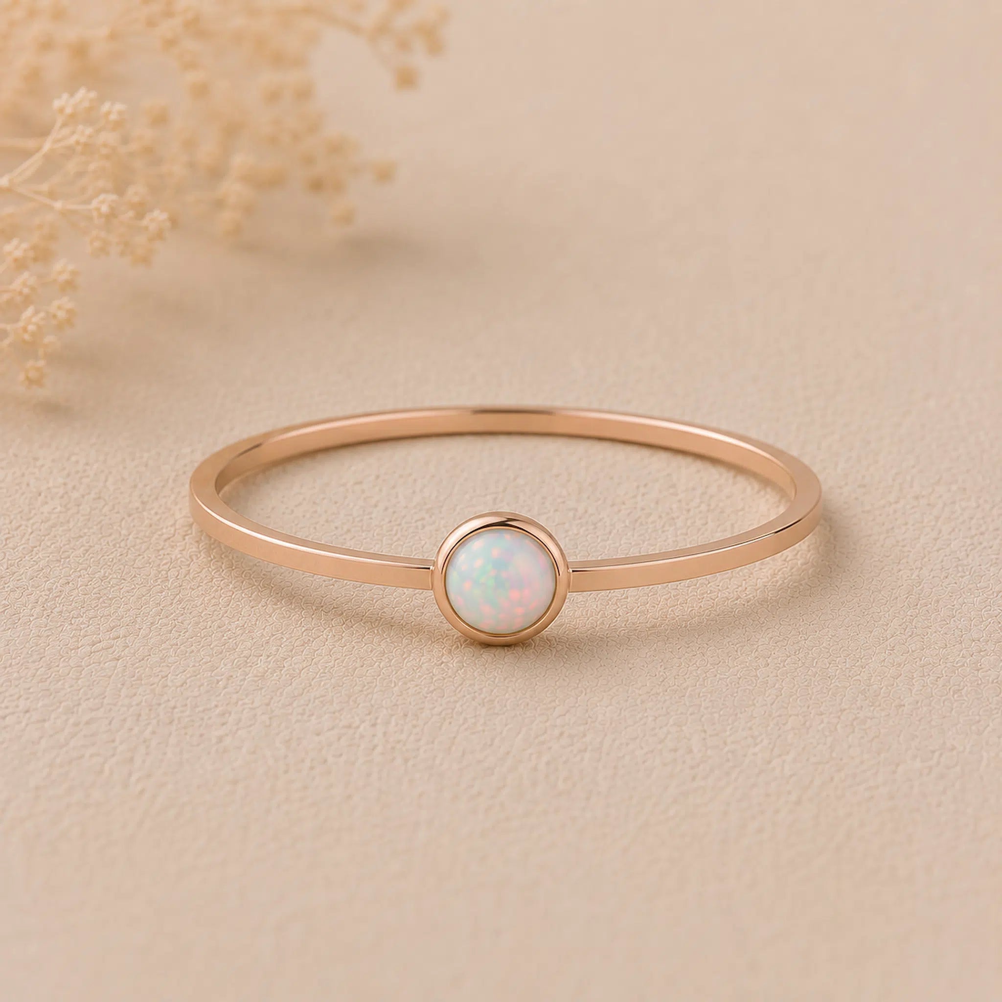 Minimalist Thin Rose gold stacker ring with a small round bezel set lab-created white opal stone on a beige background
