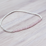 Beaded bracelet with pink rose quartz beads and silver beads on a light wooden surface