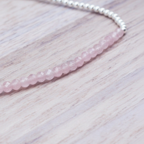 Beaded bracelet with pink rose quartz beads and silver beads on a light wooden surface