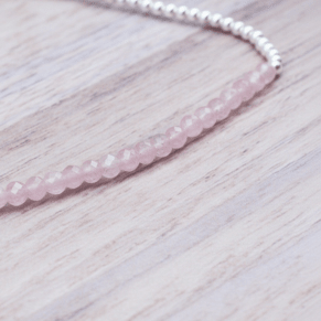Beaded bracelet with pink rose quartz beads and silver beads on a light wooden surface