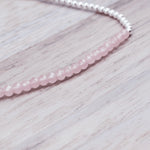 close up of a sterling silver Beaded bracelet with pink faceted rose quartz gemstone beads on a light wooden surface