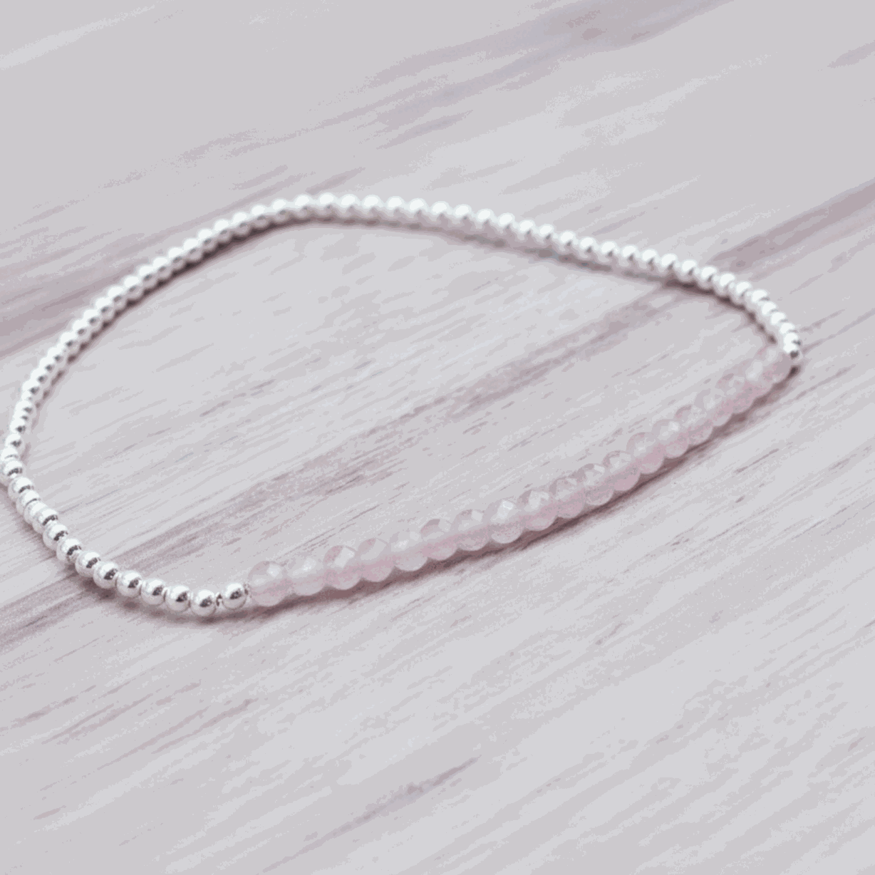 Beaded bracelet with pink beads on a light wooden surface