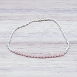 Beaded bracelet with pink beads on a light wooden surface