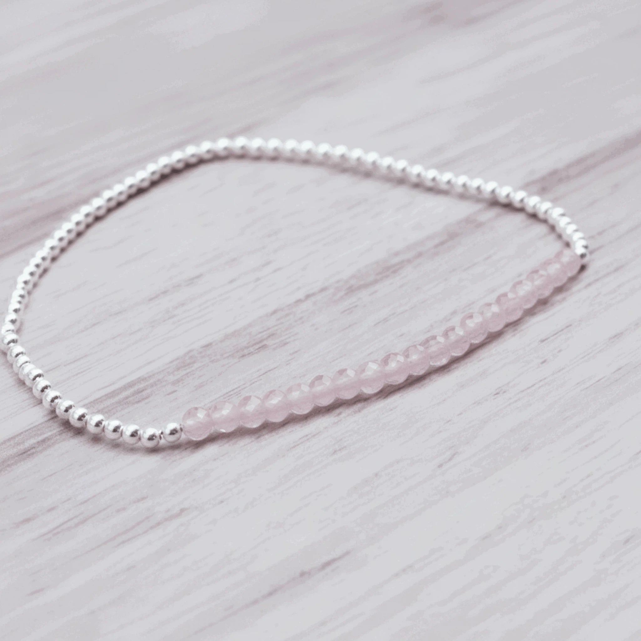sterling silver Beaded bracelet with natural pink faceted rose quartz gemstones on a light wooden surface