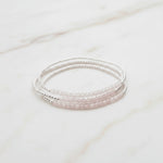 three sterling silver beaded bracelets with natural faceted light pink rose quartz gemstones on a light stone surface