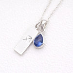 Silver sagittarius zodiac pendant necklace with a blue teardrop natural tanzanite pendant on a textured white background