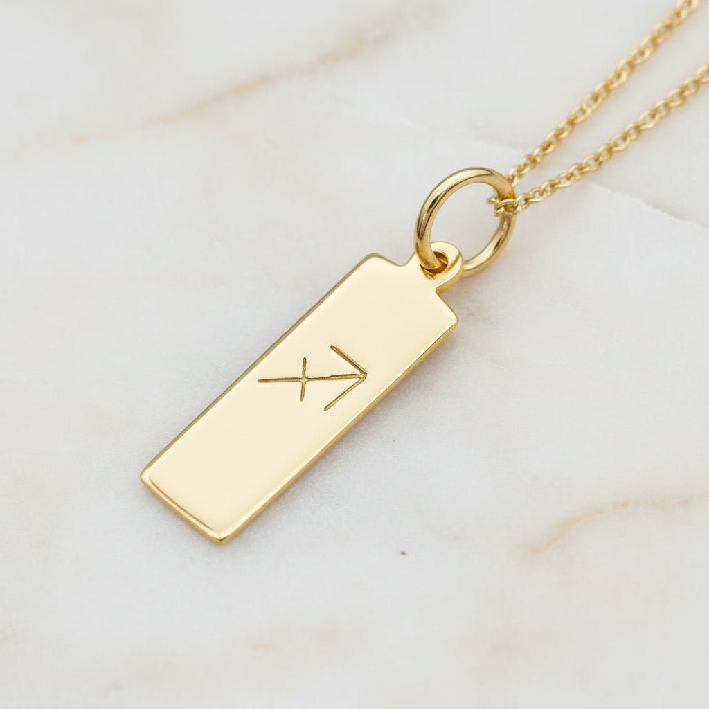 Sagittarius Zodiac Necklace in Gold Plated Sterling Silver laying on a light stone surface