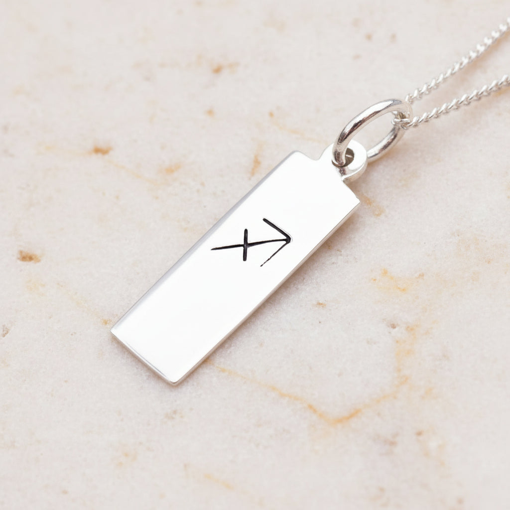 sagittarius zodiac necklace in sterling silver on a light stone surface