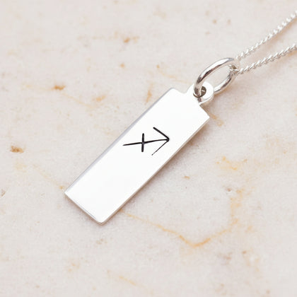sagittarius zodiac necklace in sterling silver on a light stone surface