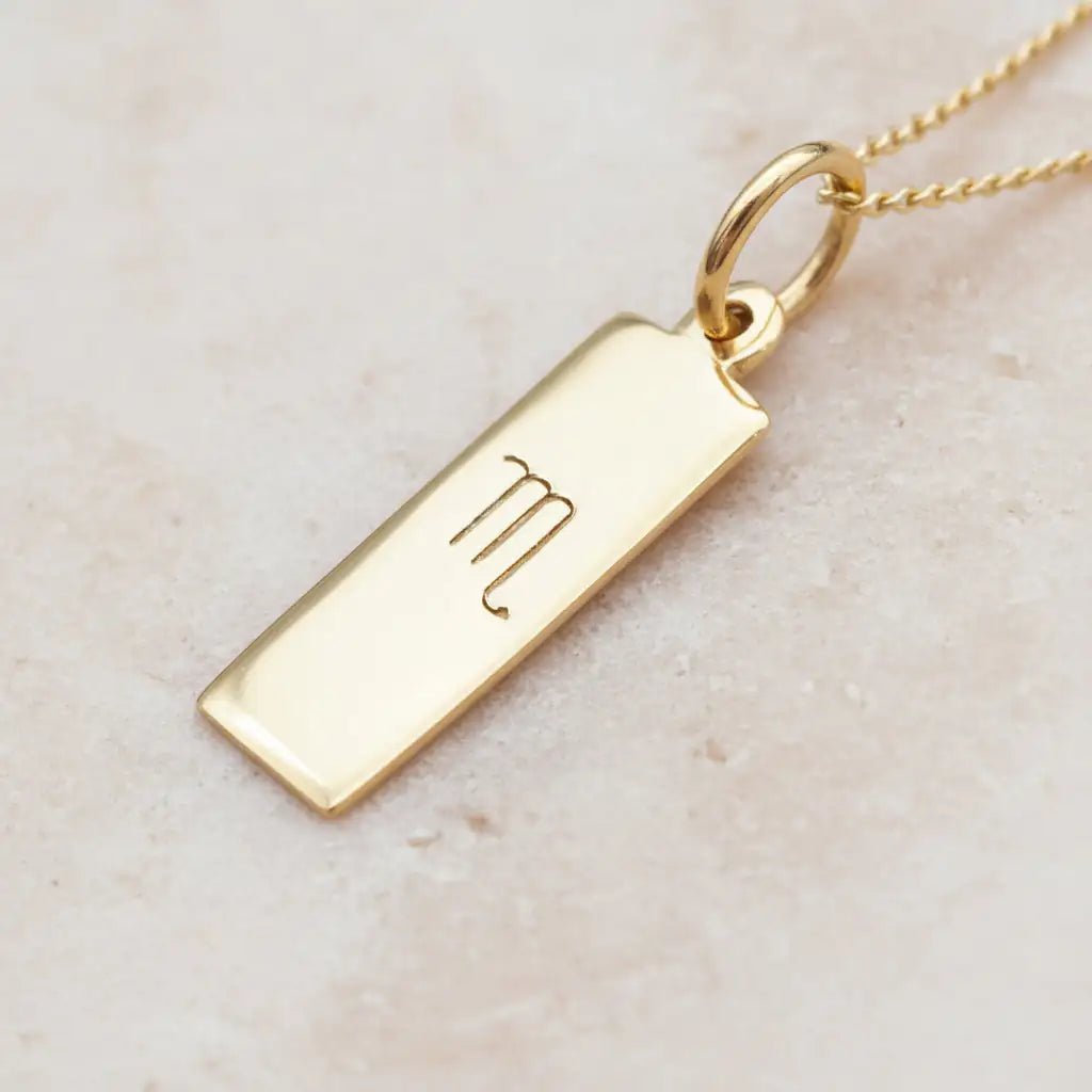 Gold Scorpio Zodiac Pendant Necklace on a light stone surface