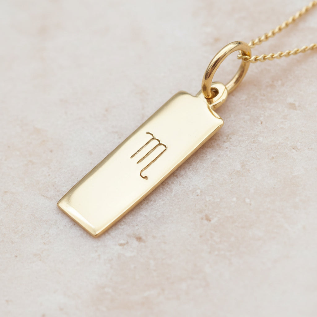 Scorpio Zodiac Necklace in Gold Plated Sterlng Silver on a light stone surface