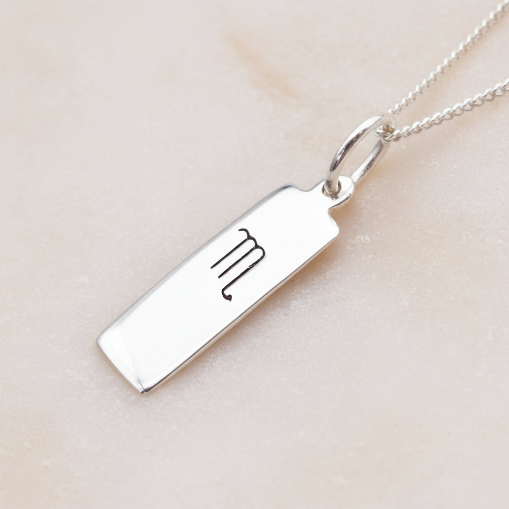 scorpio zodiac necklace in sterling silver laying on a light surface