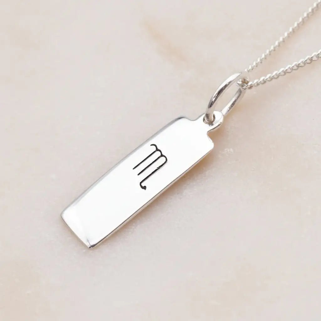 scorpio zodiac necklace in sterling silver laying on a light surface