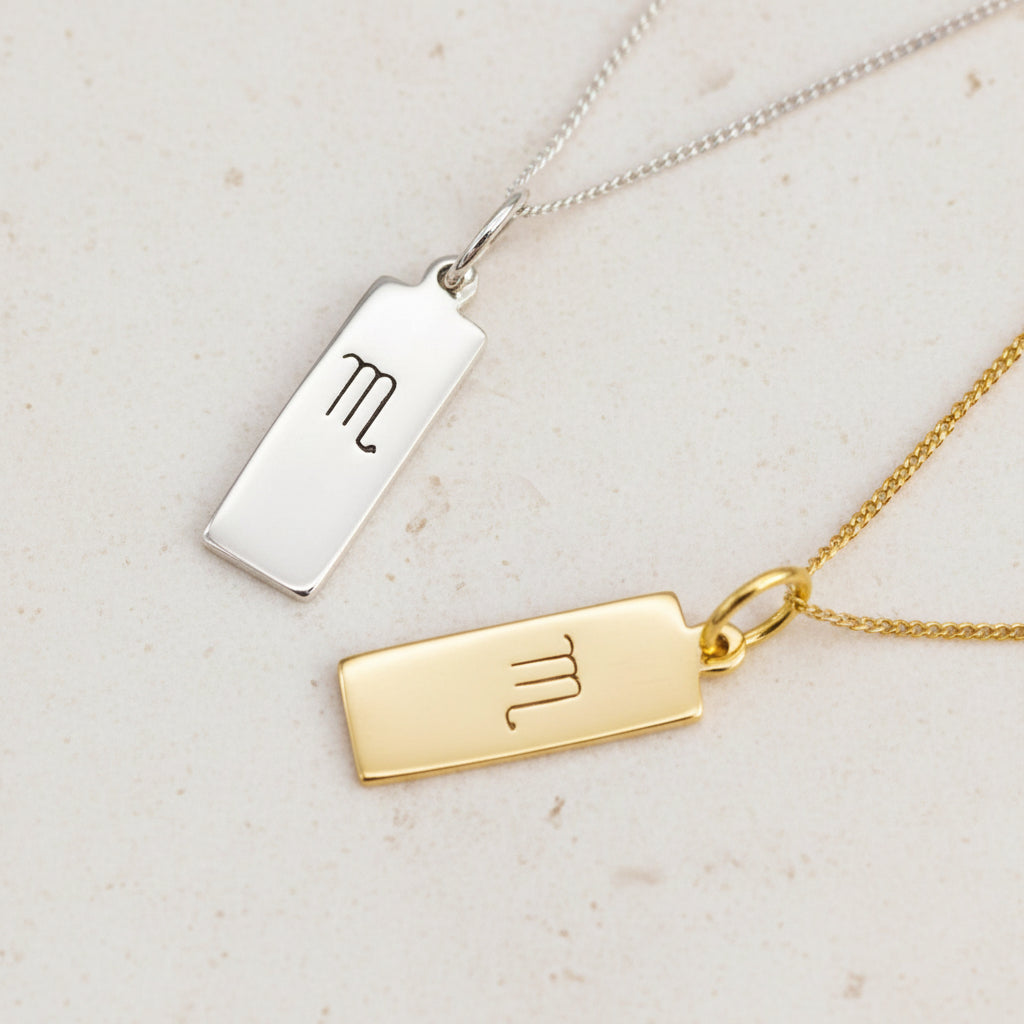 Scorpio Zodiac Necklaces in Silver and Gold on a white stone surface