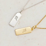 Scorpio Zodiac Necklaces in Silver and Gold on a white stone surface