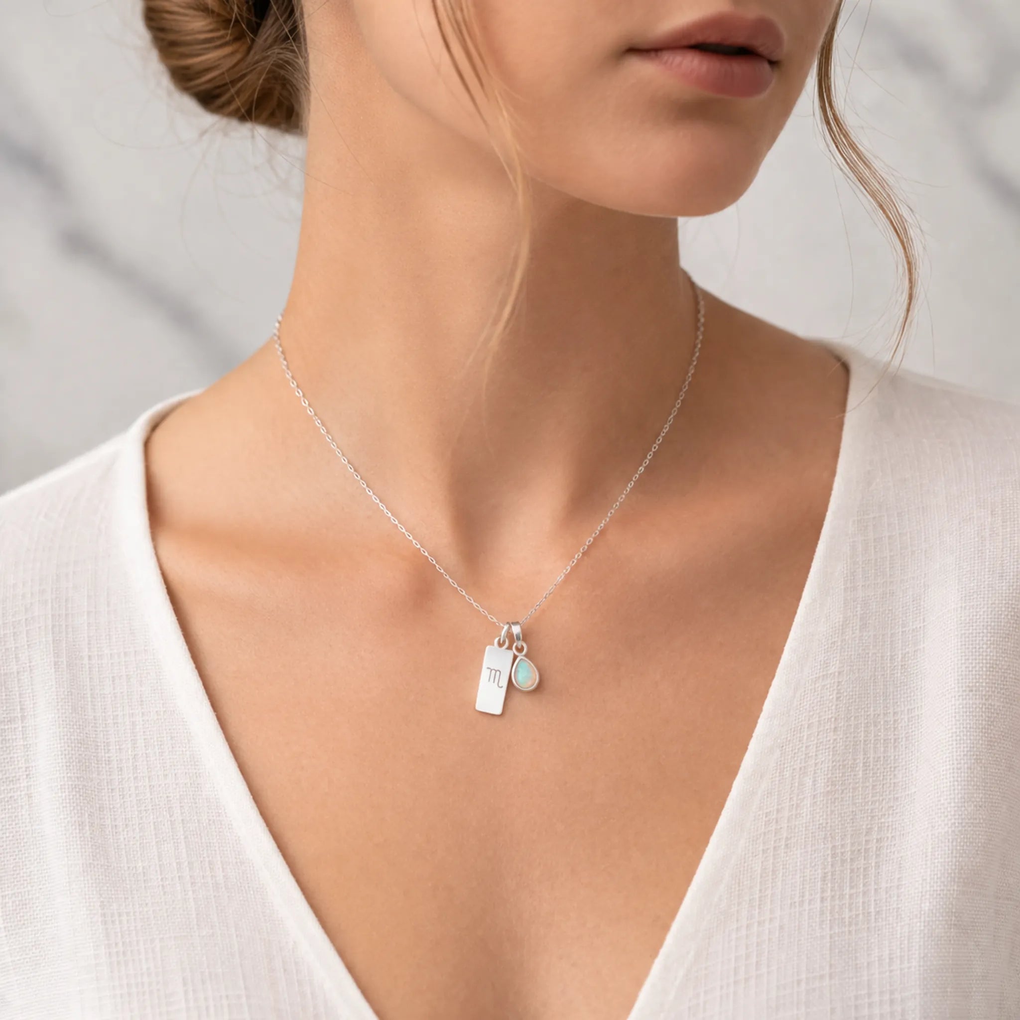 Sterling Silver Necklace with a Scorpio Zodiac Pendant and a tear drop shaped October Birthstone Opal Pendant being worn