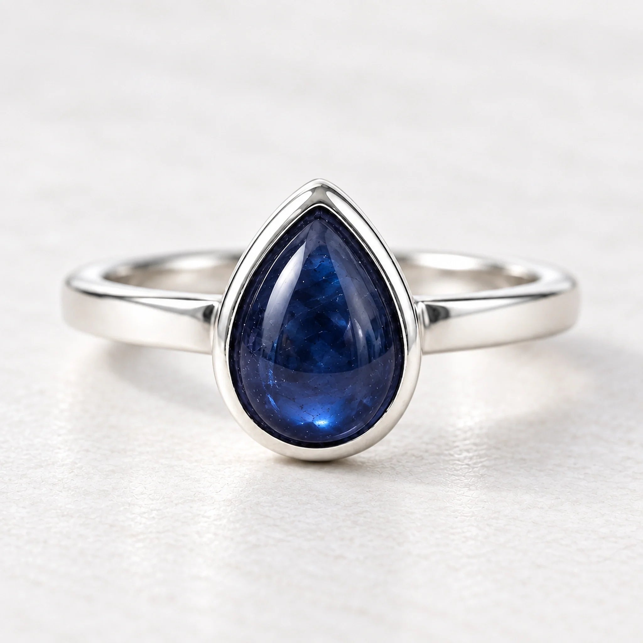 Front view of sterling silver September sapphire birthstone ring on a matte white surface