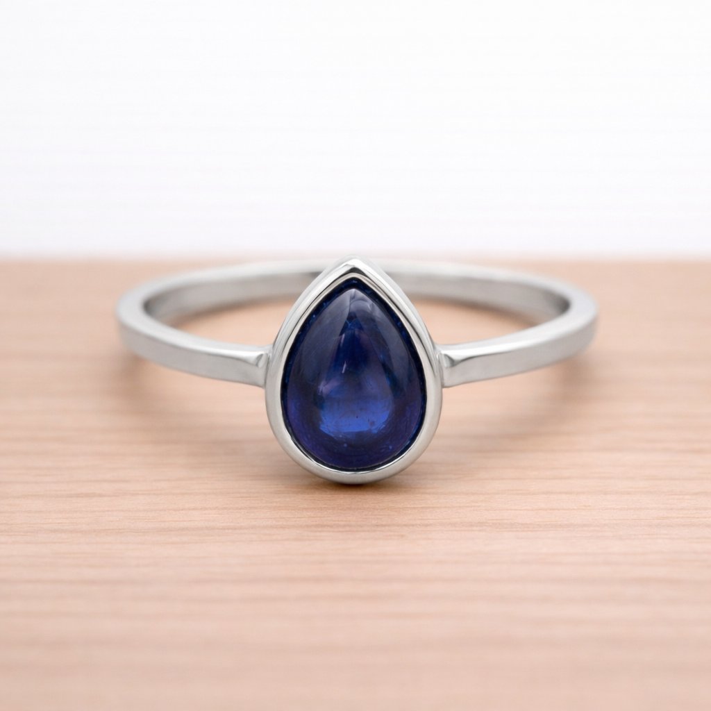 Sterling Silver ring with a blue teardrop-shaped natural Sapphire gemstone on a wooden surface