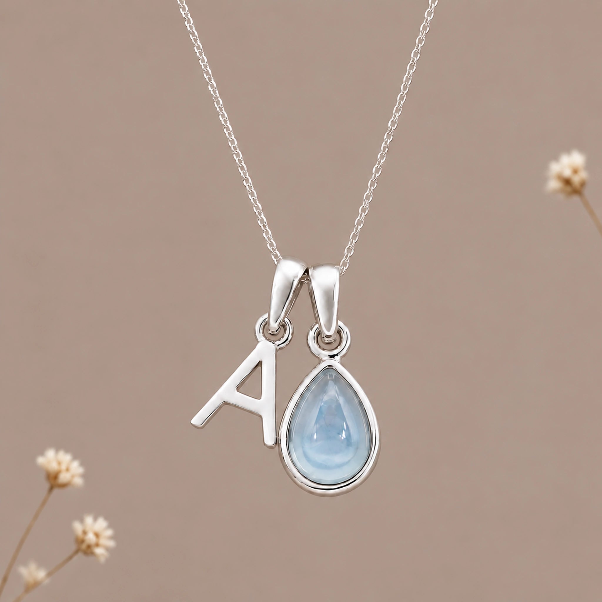 Sterling silver initial A and November natural blue topaz necklace on a taupe background with sparse ivory flowers